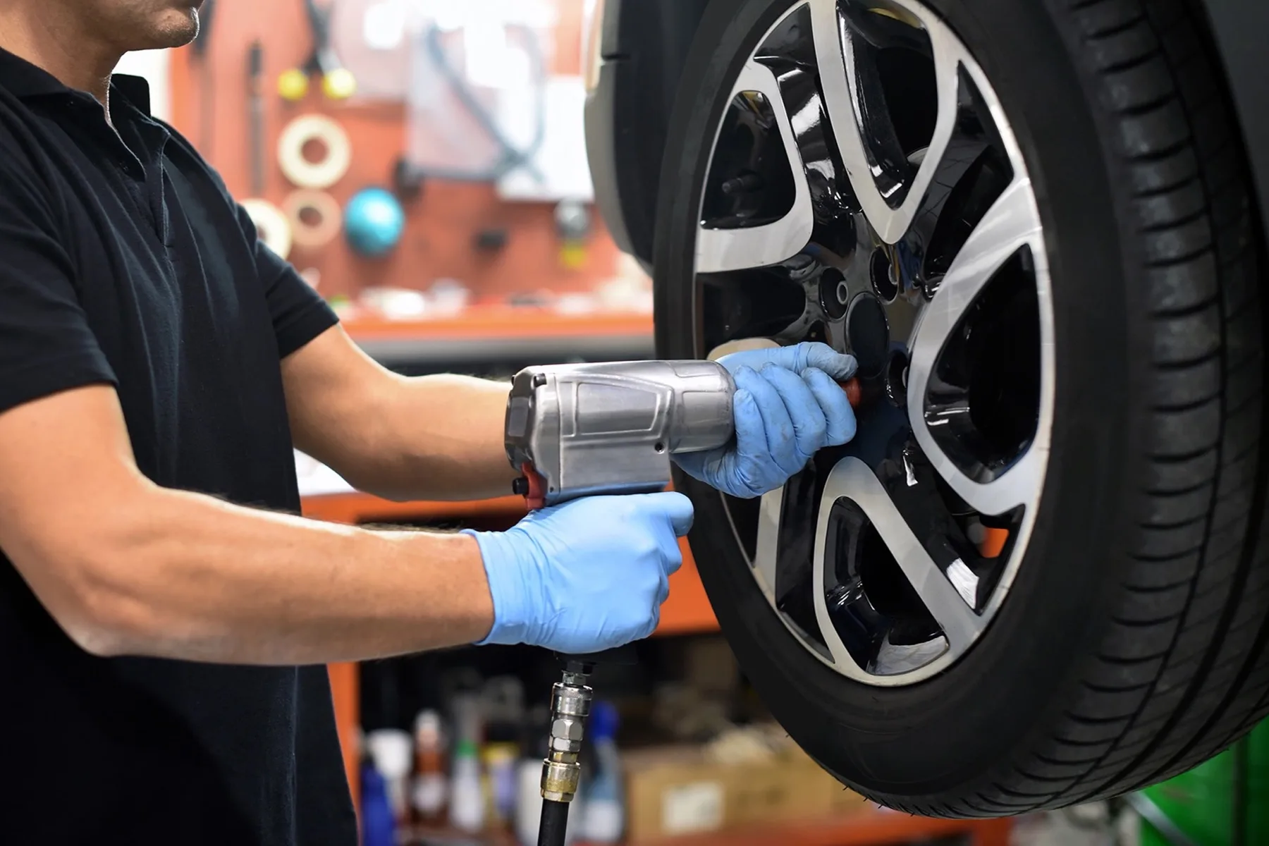 A technician running an impact driver on a wheel