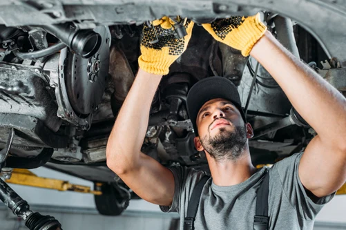 A technician working beneath a vehicle raised on a lift